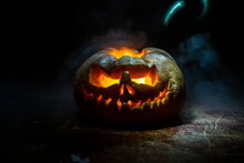 Close Up View Of Scary Halloween Pumpkin With Eyes Glowing Inside At Black Background. Selective Focus