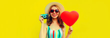 Summer Portrait Of Happy Smiling Young Woman With Film Camera And Red Heart Shaped Balloon Wearing Straw Hat On Yellow Background, Blank Copy Space For Advertising Text