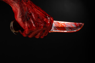 Fototapeta a man with bloody hands brandishes a knife on a black background. 