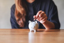 Closeup Image Of A Woman Putting Coin Into Piggy Bank For Saving Money Concept