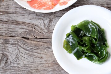 Wall Mural - Wakame seaweed and raw pork shabu on wood background