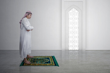 Poster - Muslim man with keffiyeh with agal in praying position (salat) on the prayer rug