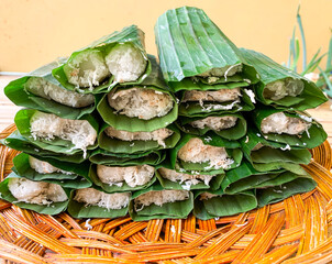 Wall Mural - A traditional Putu snack from Indonesia, made of glutinous rice, steamed on a bamboo tube and grated coconut as topping then covered with banana leaf.