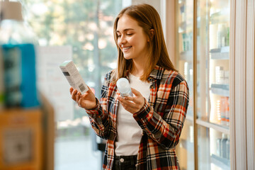 Young ginger woman smiling while choosing products in pharmacy