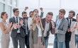 © ASDF - happy young woman standing in front of her jubilant colleagues