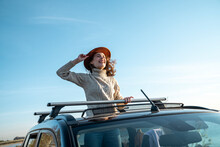 Cheerful Young Woman Wearing Hat Enjoying Through Sun Roof Of Car