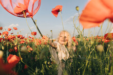 Playful Girl Playing With Red Butterfly Net In Poppy Field