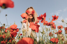 Happy Woman Covering Eyes With Flower In Poppy Field