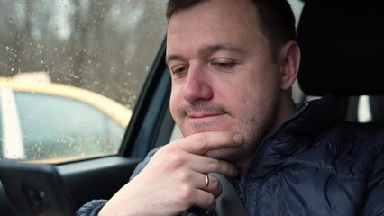 Bored confident man leaned his head on his hand and scrolled the phone screen looking through messages, news, the latest events from the lives of friends on social networks while riding in cab