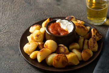 Potato bravas tapa served with beer. Spanish traditional dish made with fried poparoes and served with two hot sauces