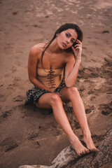 Wall Mural - Fashion posing of a brunette woman in a swimsuit and a pareo on the beach in summer, overhead shot