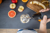 Fototapeta  - Female hands holding a hand blender for mixing fresh fruit smoothies in the kitchen. Top view, flat lay