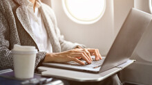 Businesswoman Using Laptop Computer During A Flight Flying To Her Destination. Cropped