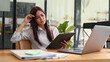 © Prathankarnpap - Serious young female employee sitting front of laptop and reading financial document
