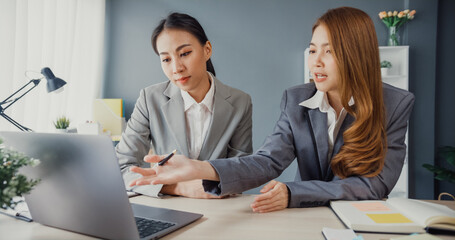 Canvas Print - Group of young asia creative team discuss project compare point in paperwork and laptop on table working and communicating together on office desk at workplace. Partner cooperation, coworker teamwork.