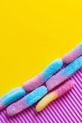 Wall Mural - Flat lay of colorful gummy sweets on pink and yellow background.