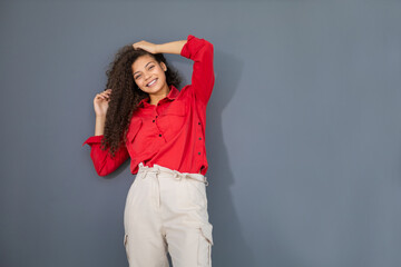 Wall Mural - Young woman in red shirt standing against grey wall