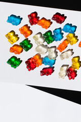 Wall Mural - Top view of colorful gummy bears on white and black background.