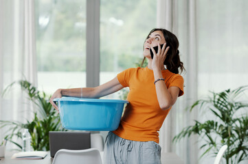 Woman collecting water leaking from the ceiling