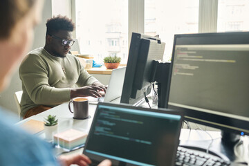 Wall Mural - Programmers working at office desk with laptops writing codes for new software