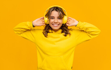 smiling attractive woman listening to music in headphones on yellow background