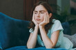 © ViDi Studio - Young frustrated sad depressed disappointed caucasian woman she 20s in casual clothes mint t-shirt prop up chin lying on blue sofa indoor rest at home in own room apartment. People lifestyle concept