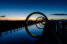 View Of The Falkirk Wheel At Sunset With Lights In Different Bright Colors
