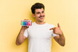 © Asier - Young caucasian man holding batteries isolated on yellow background person pointing by hand to a shirt copy space, proud and confident