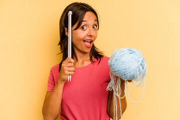 Wall Mural - Young hispanic woman holding a ball of wool isolated on yellow background