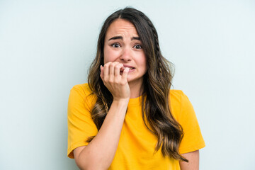 Wall Mural - Young caucasian woman isolated on blue background biting fingernails, nervous and very anxious.