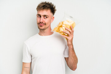 Wall Mural - Young caucasian man holding crisps isolated on white background