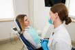 © Tania - A beautiful female dentist is talking to a patient while sitting in a chair.