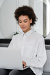 © LIGHTFIELD STUDIOS - african american woman smiling while using laptop at home.