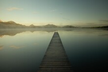 Scenic View Of A Long Wooden Pier On The Lake On A Foggy Morning