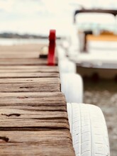 Wooden Deck Pier With White Painted Tire Wheels With A Yacht Ship On The Blurred Background