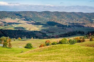 Wall Mural - Autumn fall orange colorful trees foliage and farm house land rolling hills aerial high angle view landscape in Blue Grass, Highland County, Virginia with shadows over valley