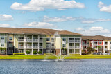Fototapeta Na ścianę - Orlando, Florida luxury lifestyle apartments buildings with three floors by lake water fountain in tropical city with blue sky clouds
