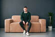 © GVS - Young trendy man posing sitting on sofa looking to camera