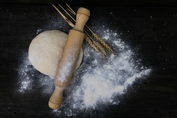 Sticker - rolling pin with wheat flour dough on wood