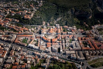 Canvas Print - Beautiful aerial top view shot of a city with terracotta roof buildings and streets around a forest