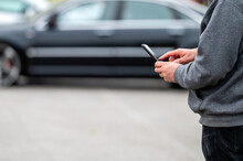 Man With Smartphone Standing Next To The Car, Using Mobile App For Paying, Car Lock  Or Internet