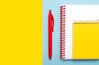 Top view of spiral notepad and red pen with space for text. Back to school concept