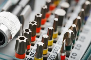 A set of different bits for screwdrivers and repairs in a box on a gray background