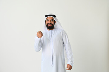 Happy Arab Emirati man UAE isolated making winning sign. Arabian Muslim businessman success concept wearing traditional