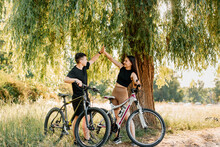 Young Couple Riding A Bicycle In The Park