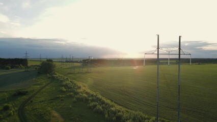 Wall Mural - High voltage electric power tower in a green agricultural landscape at beautiful sunset