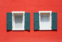 Two Italian Windows On The Red Wall Facade With Open Green Color Classic Shutters