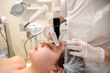 Wall Mural - Close up side portrait of beautiful young woman getting anti-aging rejuvenation treatment in beauty salon