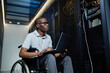 © Seventyfour - Portrait of young man with disability working as IT technician and managing server network, copy space