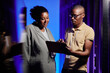 © Seventyfour - Waist up portrait of black adult man and woman using tablet in server room while setting up data network